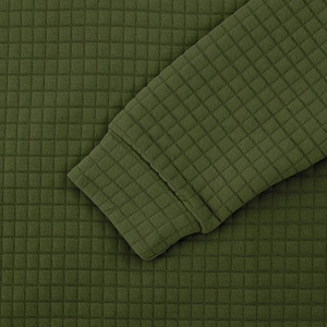 Macro detail of military green checkered quilted fabric and cuff stitching on men's sweatshirt