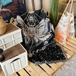 Close-up of woven bohemian outdoor blanket featuring mystic moth and moon phase patterns