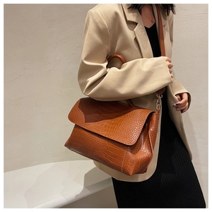 Detail of brown crocodile pattern shoulder bag with handle and adjustable strap