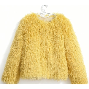 Close-up of fluffy yellow faux fur coat texture and long shaggy Mongolian wool style fabric