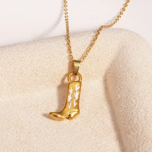 Vue détaillée du pendentif botte de cow-boy doré avec émail blanc sur surface douce