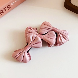 Detail showing set of three elegant pink silk bow hair clips with a soft satin finish