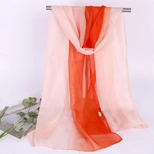 Close-up of pink and orange gradient chiffon scarf hanging on a gold metal rod