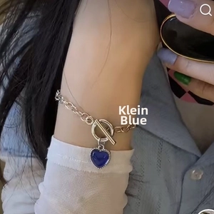Detail showing a Klein Blue heart pendant on a silver OT buckle necklace worn by a model