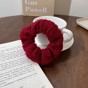 Detail of burgundy teddy fleece scrunchie with plush texture on a vintage book