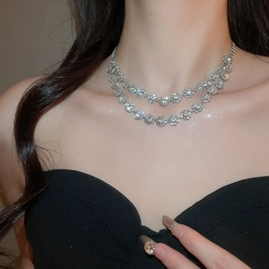 Close-up of a layered silver necklace with sparkling rhinestone floral pendant on a model