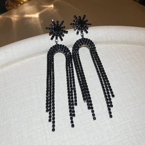 Detailed view of long black tassel earrings featuring star shape and rhinestone inlay