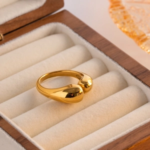 Close-up of a polished gold teardrop open ring placed in a luxury wooden jewelry box