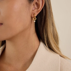 Gros plan de boucles d'oreilles à pampilles dorées avec zircon sur le modèle