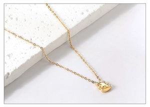 Gros plan du collier pendentif dinosaure doré avec cristal étincelant sur pierre blanche