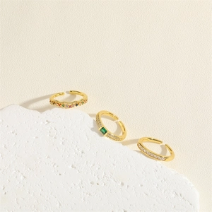 Minimalist gold adjustable rings with emerald zircon and colorful gemstones on stone