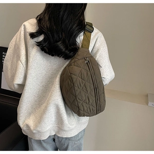 Detail of army green quilted crossbody bag with olive strap shown on model back