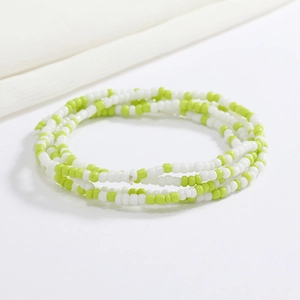 Macro shot of green and white glass seed bead body chain on a clean white background