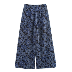 Detailed view of black straight-leg pants featuring intricate blue floral embroidery texture