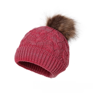 Detailed macro view of hot pink cable knit winter hat with a brown faux fur pom pom