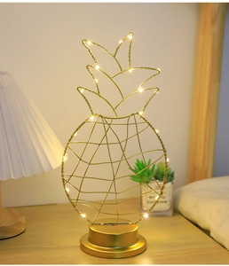 Detail of pineapple-shaped gold wire LED decorative lamp on a cozy bedside table