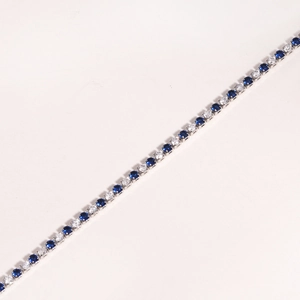 Detail of tennis bracelet with alternating blue and white cubic zirconia in claw setting