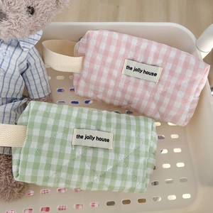 Detailed macro view of quilted plaid makeup bag texture and woven label with handle