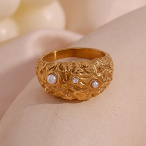 Macro shot of 18K gold textured wide ring with inlaid pearls and sparkling zircon