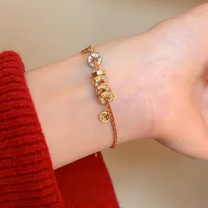 Bracelet cordon rouge plaqué or avec breloques pièces de monnaie et cristaux brillants