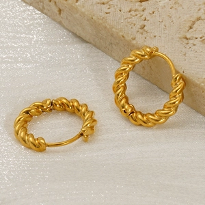 Minimalist gold plated stainless steel twisted hoop earrings on natural stone background