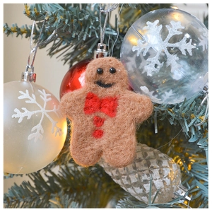 Close-up of a plush felt gingerbread man ornament hanging on a Christmas tree branch