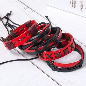 Close-up of multilayer red and black leather woven bracelets on a white wood surface