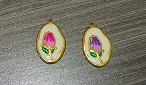 Detailed macro view of two gold-plated tulip flower enamel pendants for jewelry making