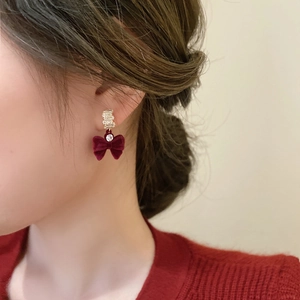 Gros plan de boucles d'oreilles nœuds en velours bordeaux avec détails en strass brillants