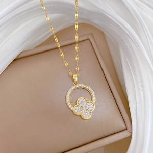 Detail of gold four-leaf clover pendant with sparkling pave crystals on jewelry box