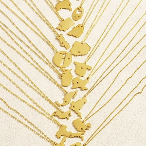 Minimalist gold country map outline necklaces with hollow heart detail on art background