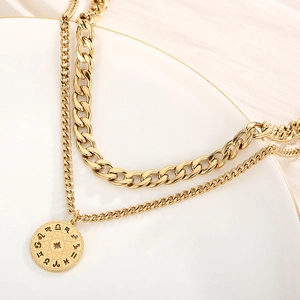 Macro detail of gold layered zodiac pendant necklace with thick cuban chain and star engraving