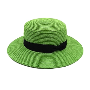 Detail of bright green flat top straw hat featuring a black ribbon bow contrast