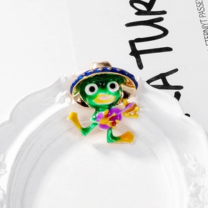 Cute green enamel frog brooch wearing a blue hat and playing an instrument