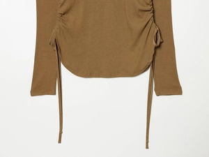 Detail view of brown long sleeve knitted top featuring side drawstring ruched texture