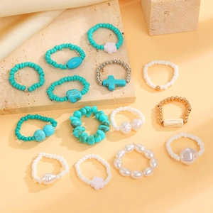 Flat lay of 13-piece bohemian ring set with turquoise, pearls, and golden cross charms