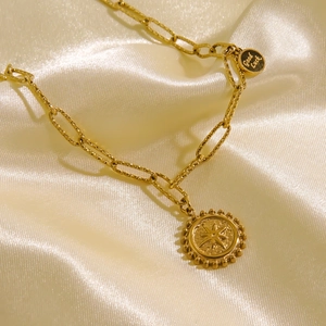 Dettaglio collana a catena d'oro con pendente Good Luck e bussola su seta di lusso