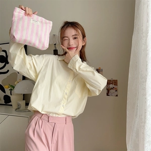 Pink striped canvas makeup bag with Feel the Sun label held by a female model