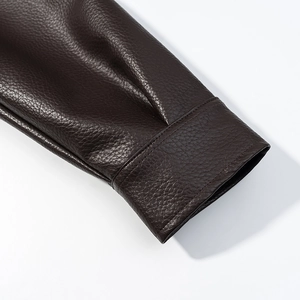 Gros plan du poignet de la veste en cuir marron foncé montrant texture et coutures