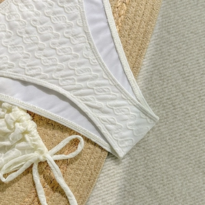 Makro-Detail von weißem strukturiertem Bikini-Stoff mit 3D-Wellenmuster und Träger