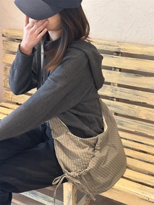 Close-up of khaki plaid nylon croissant bag with drawstring detail and soft texture