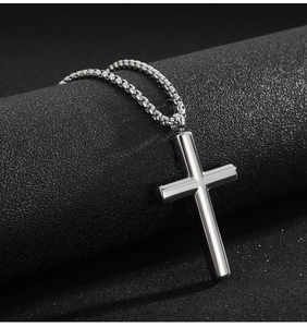 Macro shot of silver polished stainless steel cross pendant on black textured background