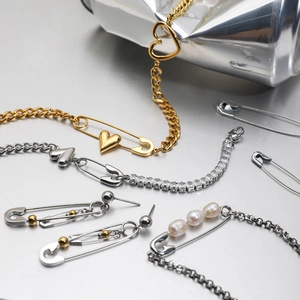 Close-up of safety pin style bracelets and earrings with pearls on industrial metal surface