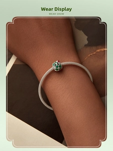 Silver mesh bracelet with a green clover enamel charm bead on a model's wrist