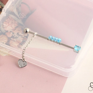 Detailed view of silver stainless steel industrial barbell with blue beads and heart charm