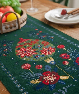 Close-up of green Christmas table runner with festive jacquard pine and berry patterns