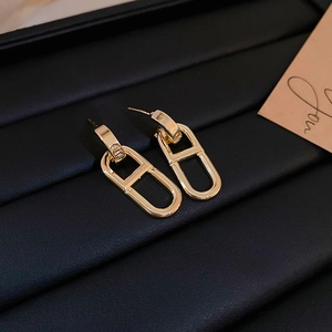 Detailed close-up of golden anchor link earrings on a textured black leather surface