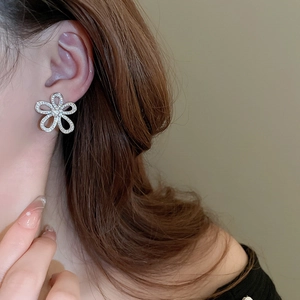 Close-up of elegant silver flower stud earring with sparkling crystals on female model
