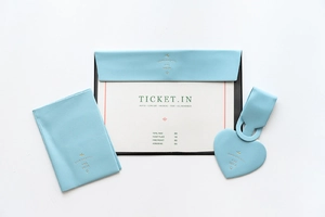 Flat lay of light blue faux leather luggage tags and travel organizers with gold foil text