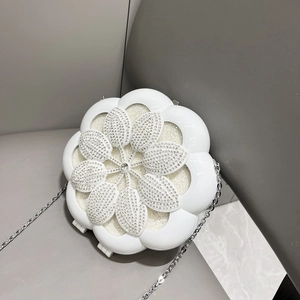 Detailed top view of a white camellia flower evening bag with sparkling rhinestones and silver chain